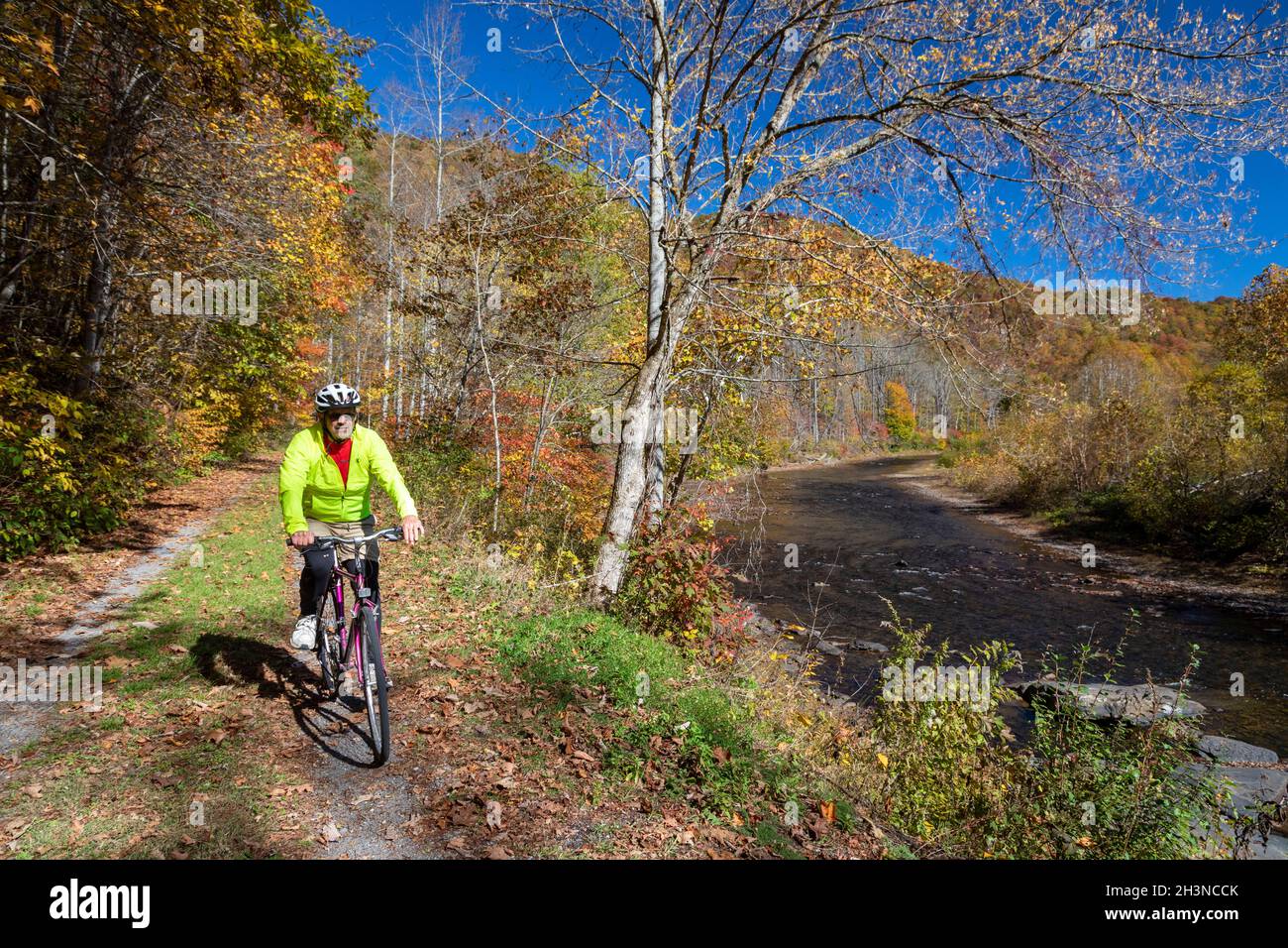Martinton, West Virginia - John West, 75, bicycles on the Greenbrier River Trail. The 78-mile rail trail runs along the Greenbrier River. Now a linear Stock Photo