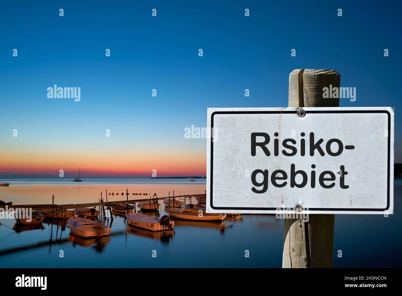 Sign with the inscription Risk area (Risikogebiet). Due to many new corona infections, areas are d Stock Photo