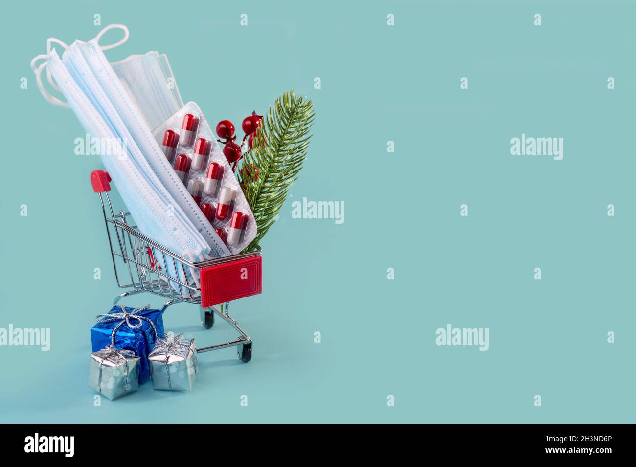 Christmas medical card with masks, pills in a shopping cart, and gift boxes. Stock Photo