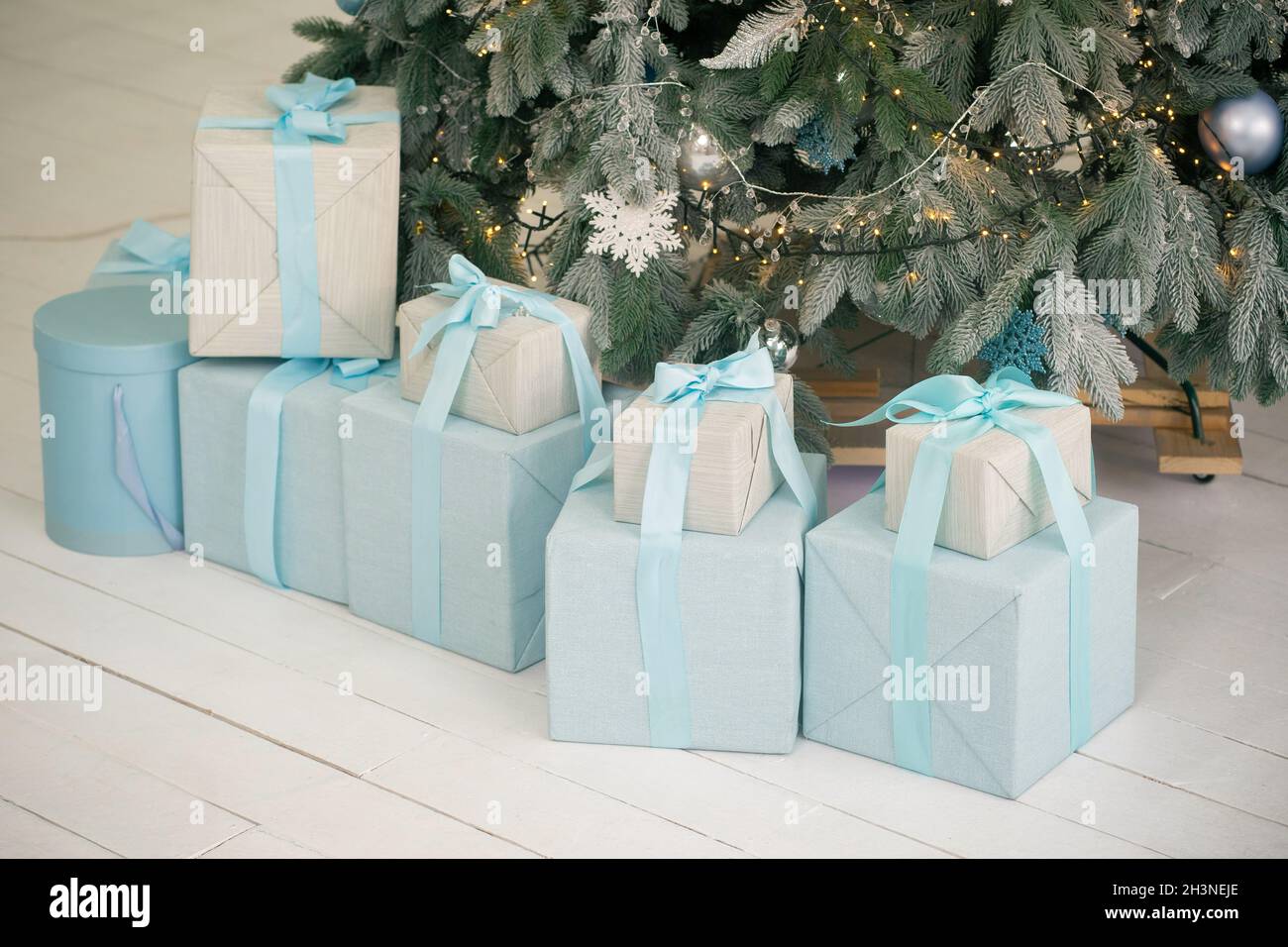 New Year gifts under Christmas tree on white floor Stock Photo