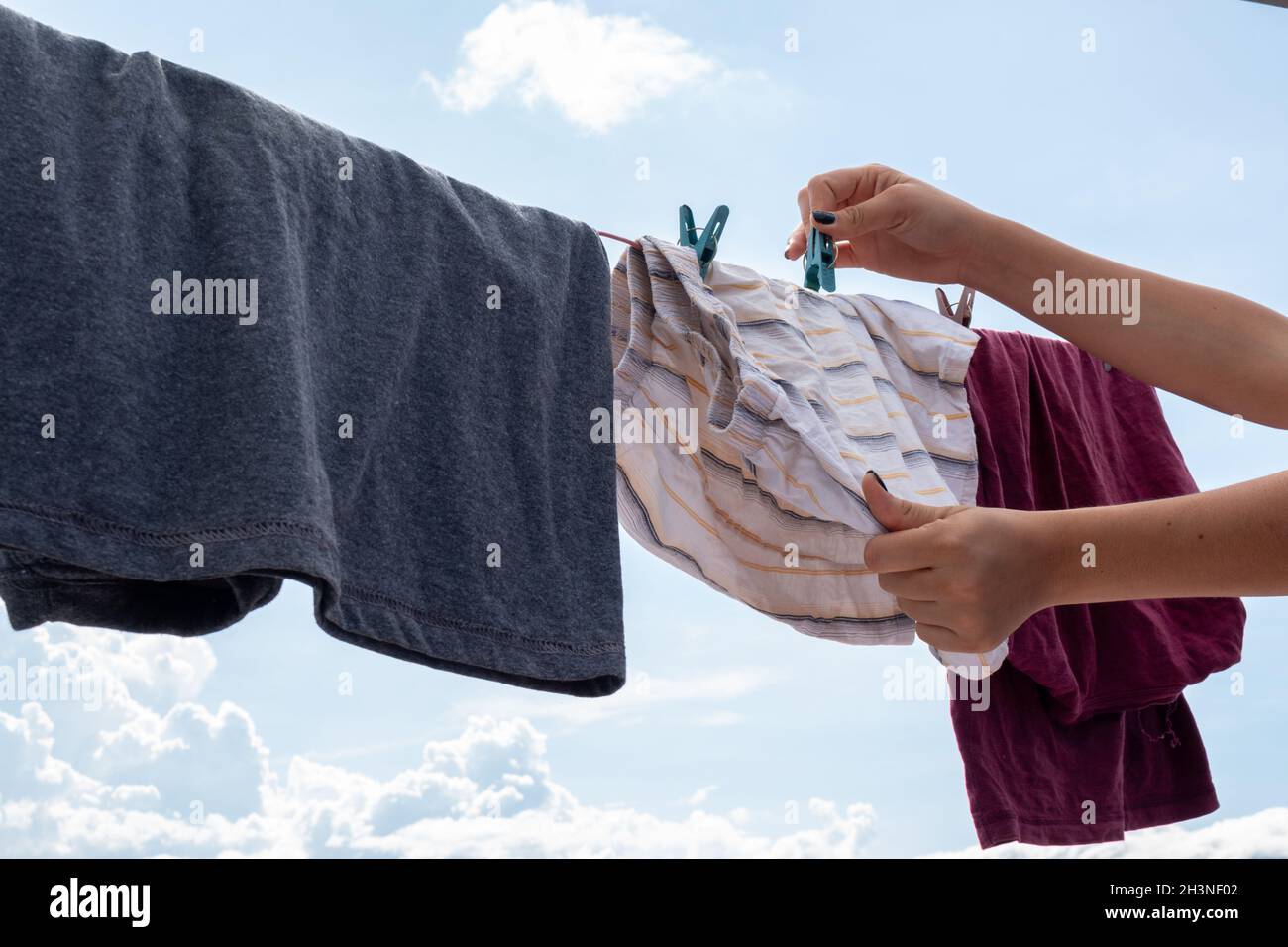 woman's hand hanging clothes on outside clothesline Stock Photo