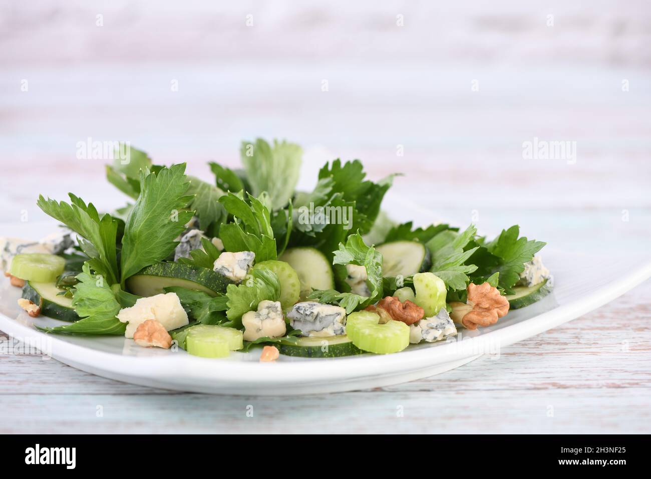 Celery leaves and stalks salad with fresh cucumber slices, blue cheese, crushed nuts. Stock Photo