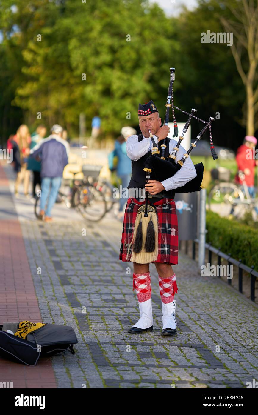 Street musician with bagpipe on the beach promenade of Swinoujscie in Poland Stock Photo
