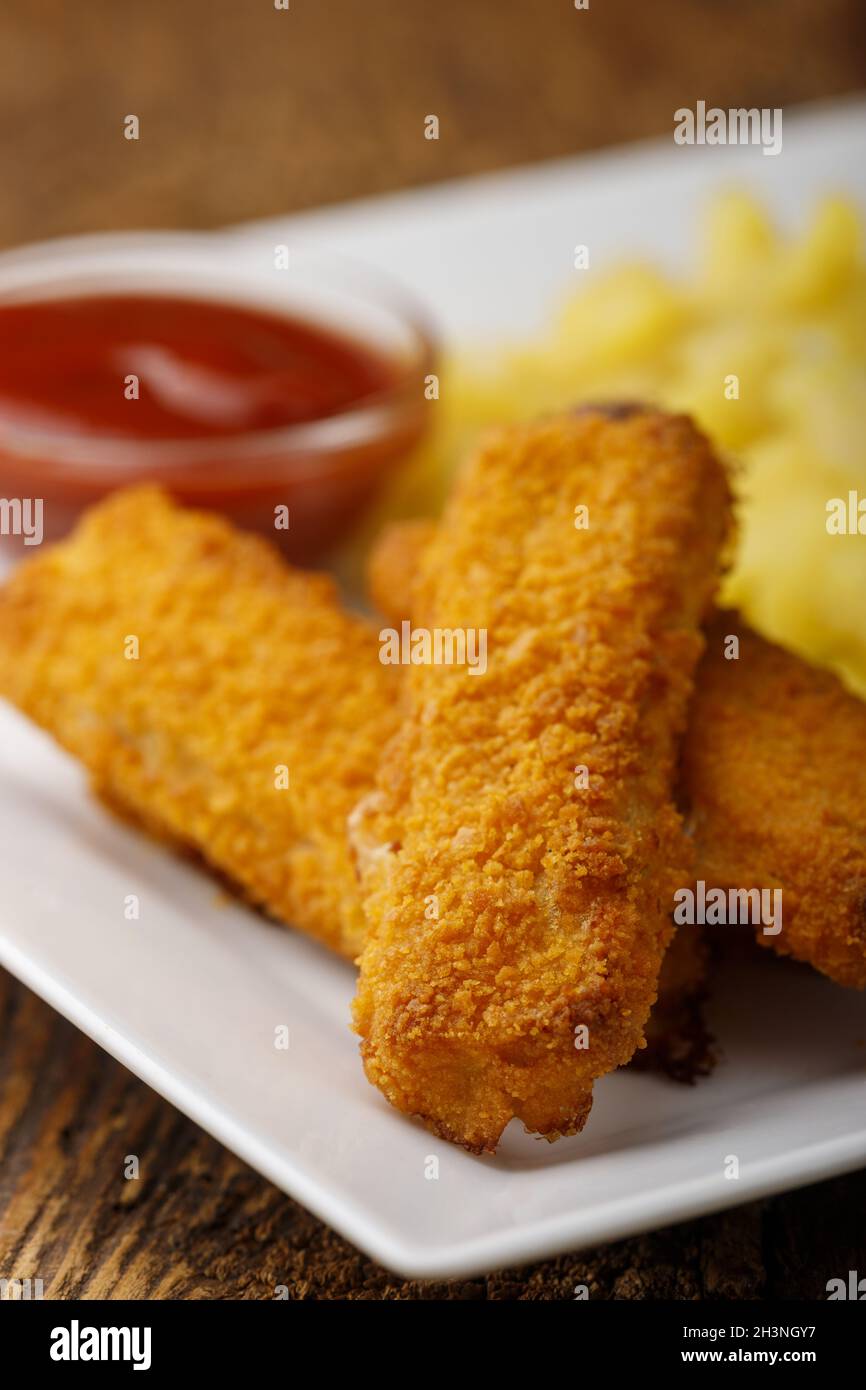 Fish fingers with potato salad on the plate Stock Photo