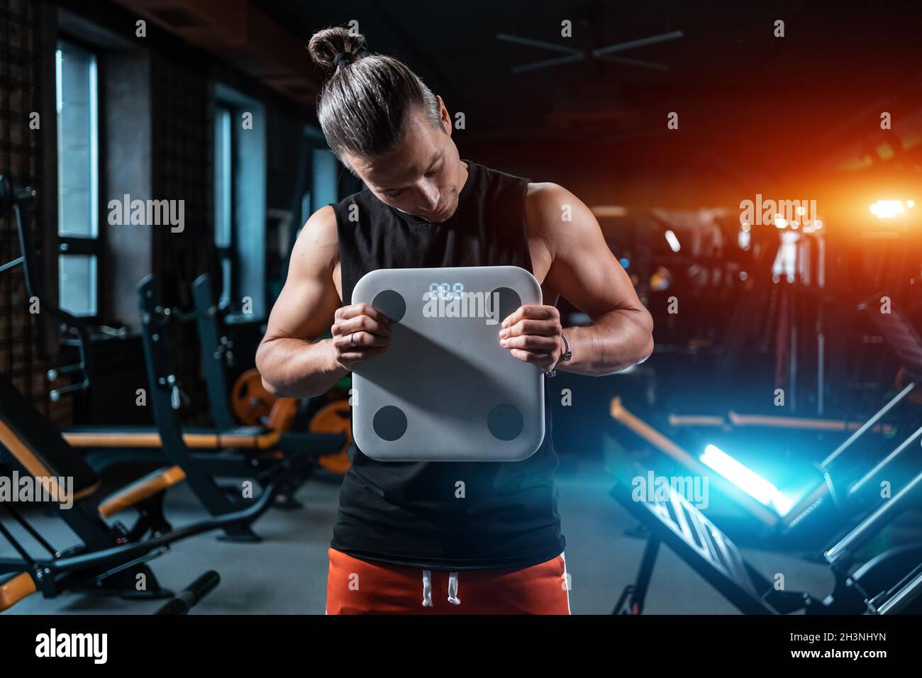 young attractive athlete male weight with scale in gym and dieting Stock Photo