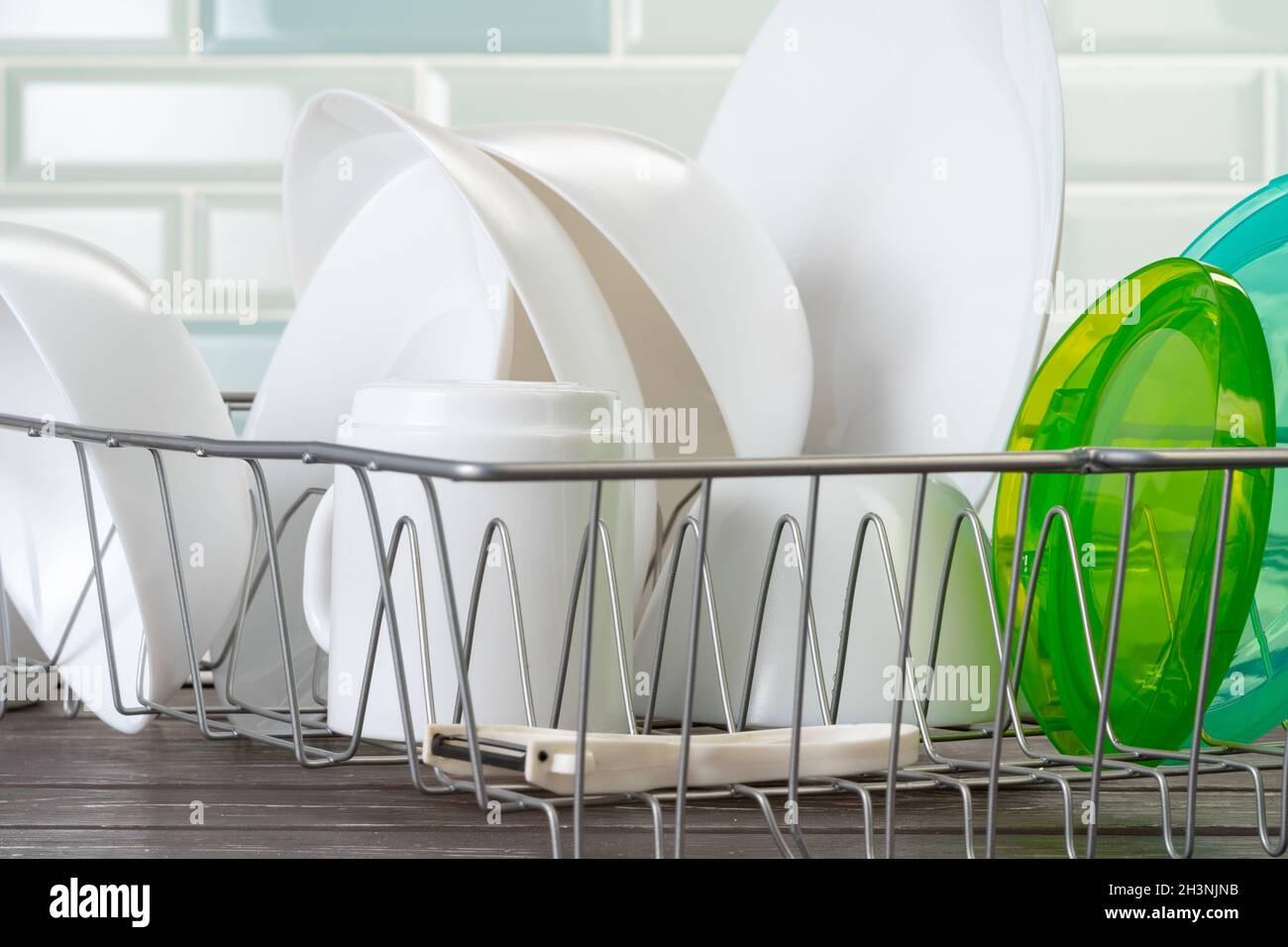 Dish rack with clean dry dishes on kitchen counter Stock Photo