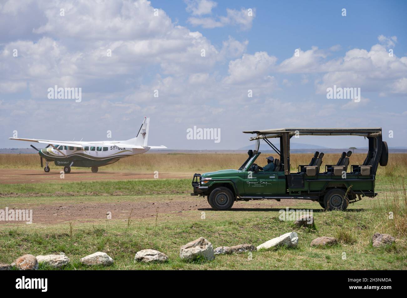 4x4 Toyota Landcruiser safari vehicle waits as a light aircraft taxis on the Musiara airstrip, Masai Mara, Kenya Stock Photo