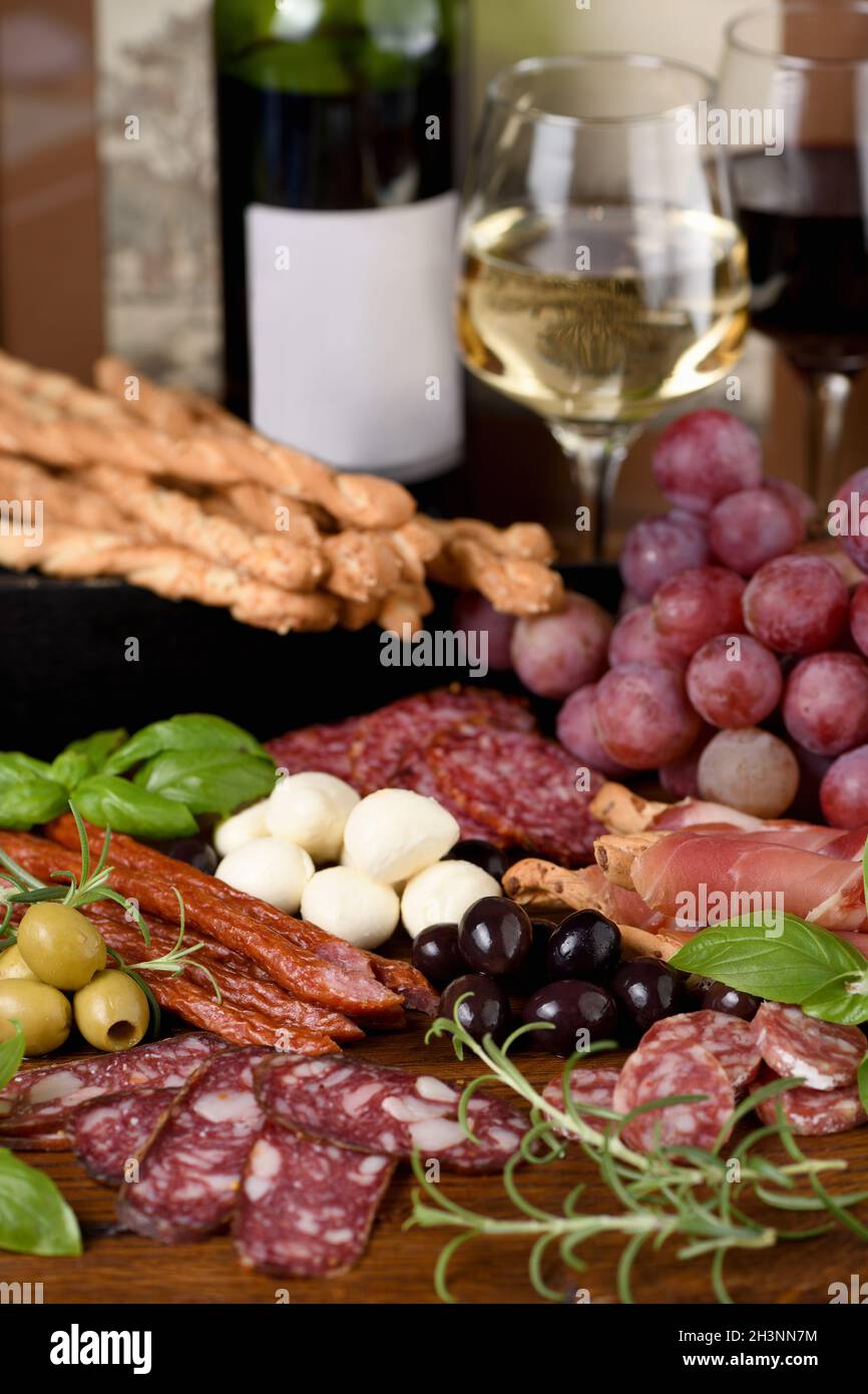 Antipasto. Dish with sausage, dried ham, salami, crispy grissini with grapes. A meat appetizer