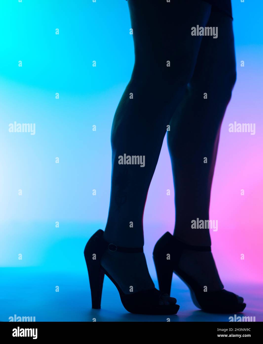 Sexy curvy lady's legs and high heel stiletto shoes in disco dance lights nightclub. Stock Photo