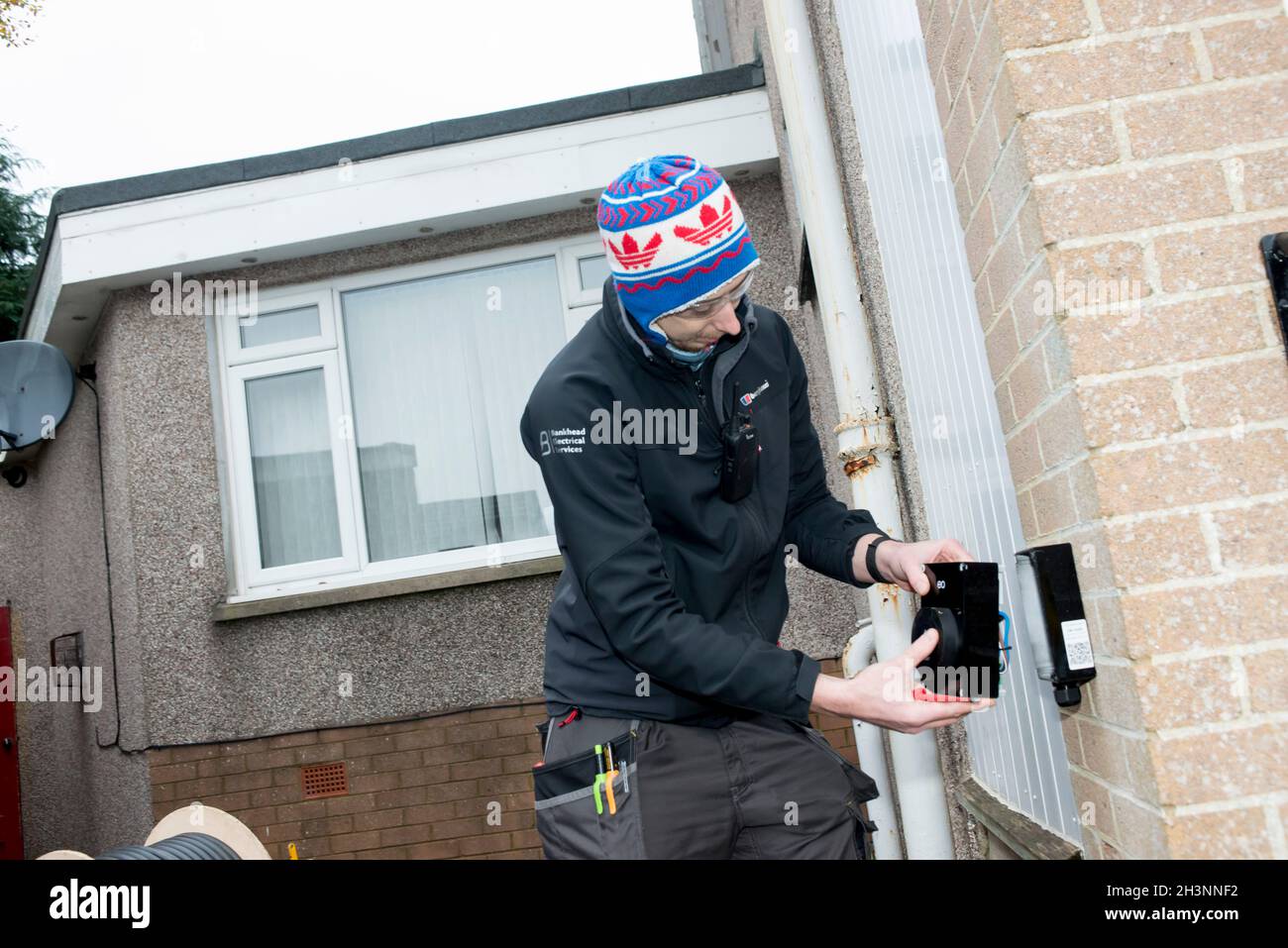 Installing an electric car home charging point on a house in Aberdeen Scotland Stock Photo