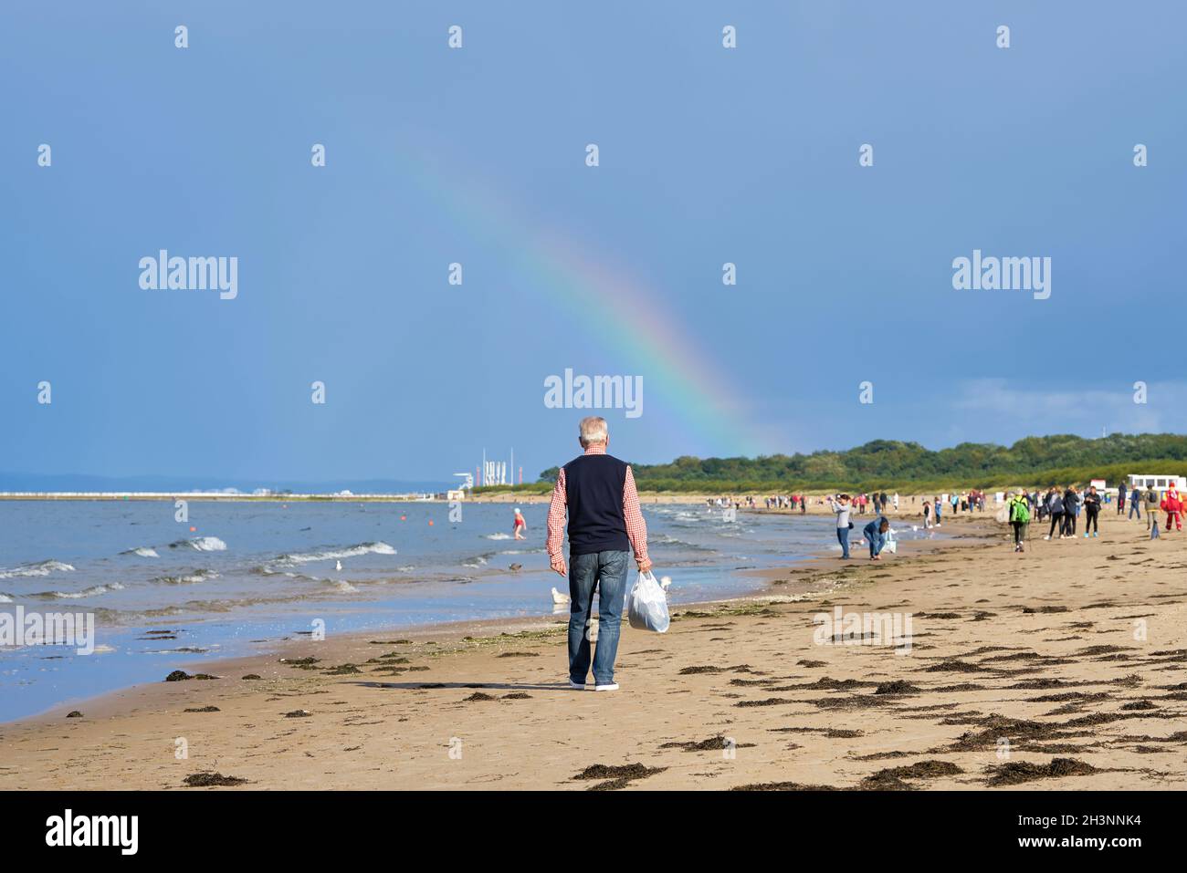 Holidaymakers on the beach of Swinoujscie on the Baltic Sea. In the background a rainbow. Stock Photo