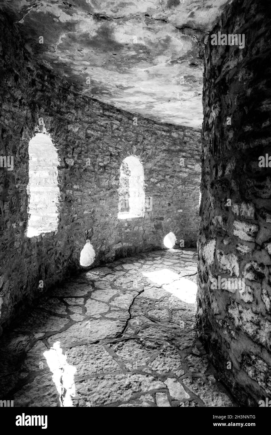 Vertical grayscale shot of a an old fortress with window openings from inside Stock Photo