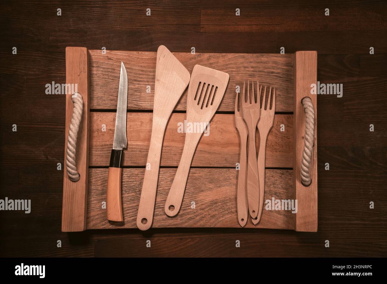 Wooden kitchen utensils laid out on wooden tray on wooden table