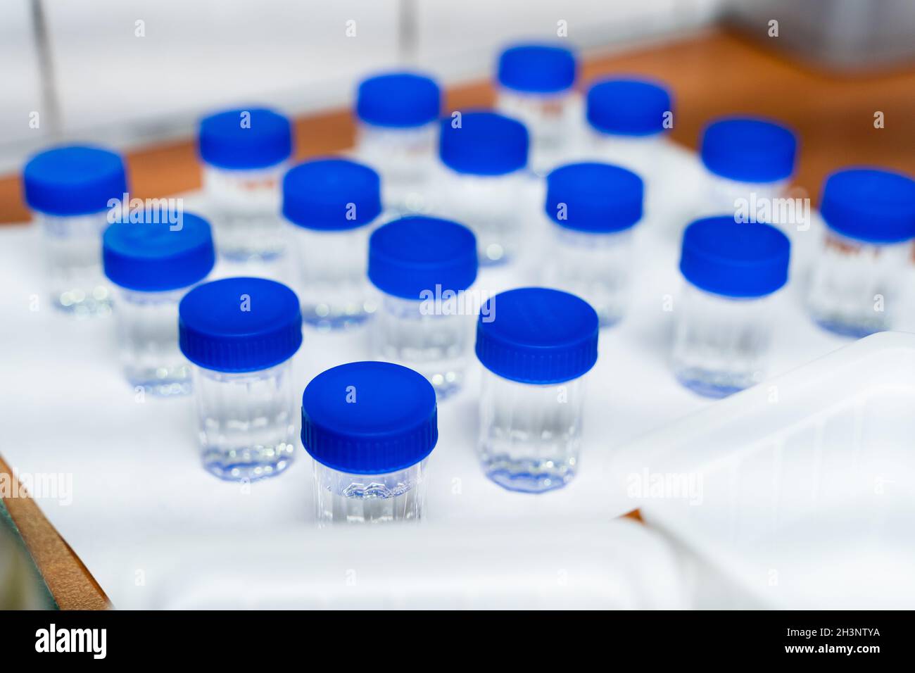 Test tubes with blue cap and transparent liquid in laboratory. Quality