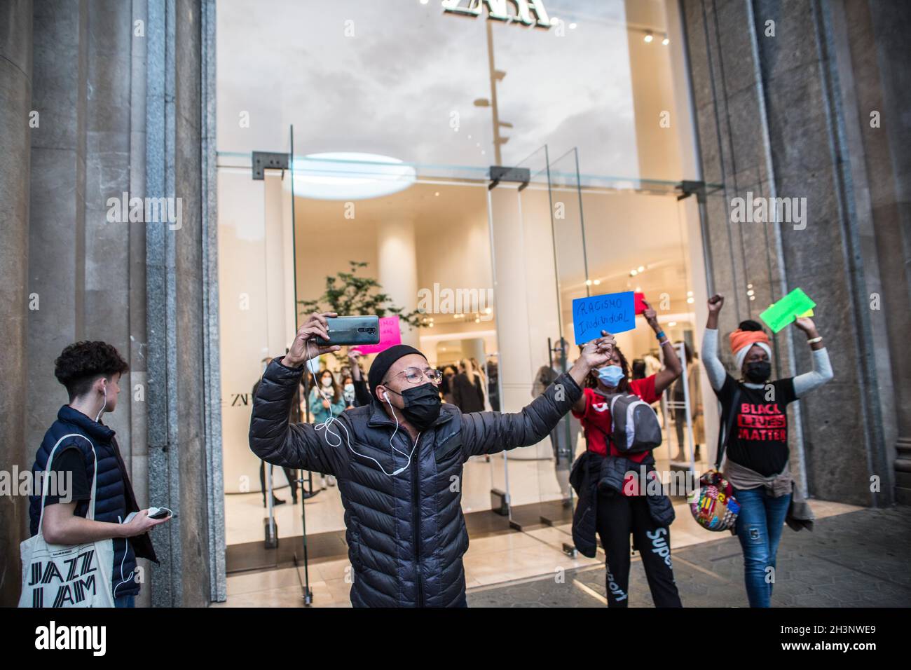 A protester holding a placard that reads, individual racism, during the  demonstration.A group of Brazilian activists in Barcelona have held a  demonstration inside and outside the main Spanish clothing store, Zara,  escalated