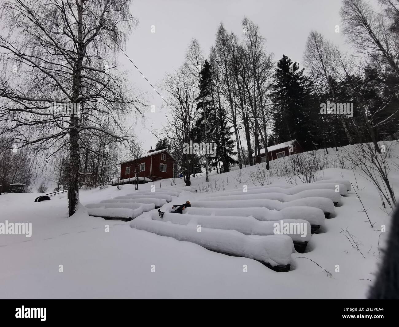 A man laying on the snow covered stairs in front of a cabin. Stock Photo