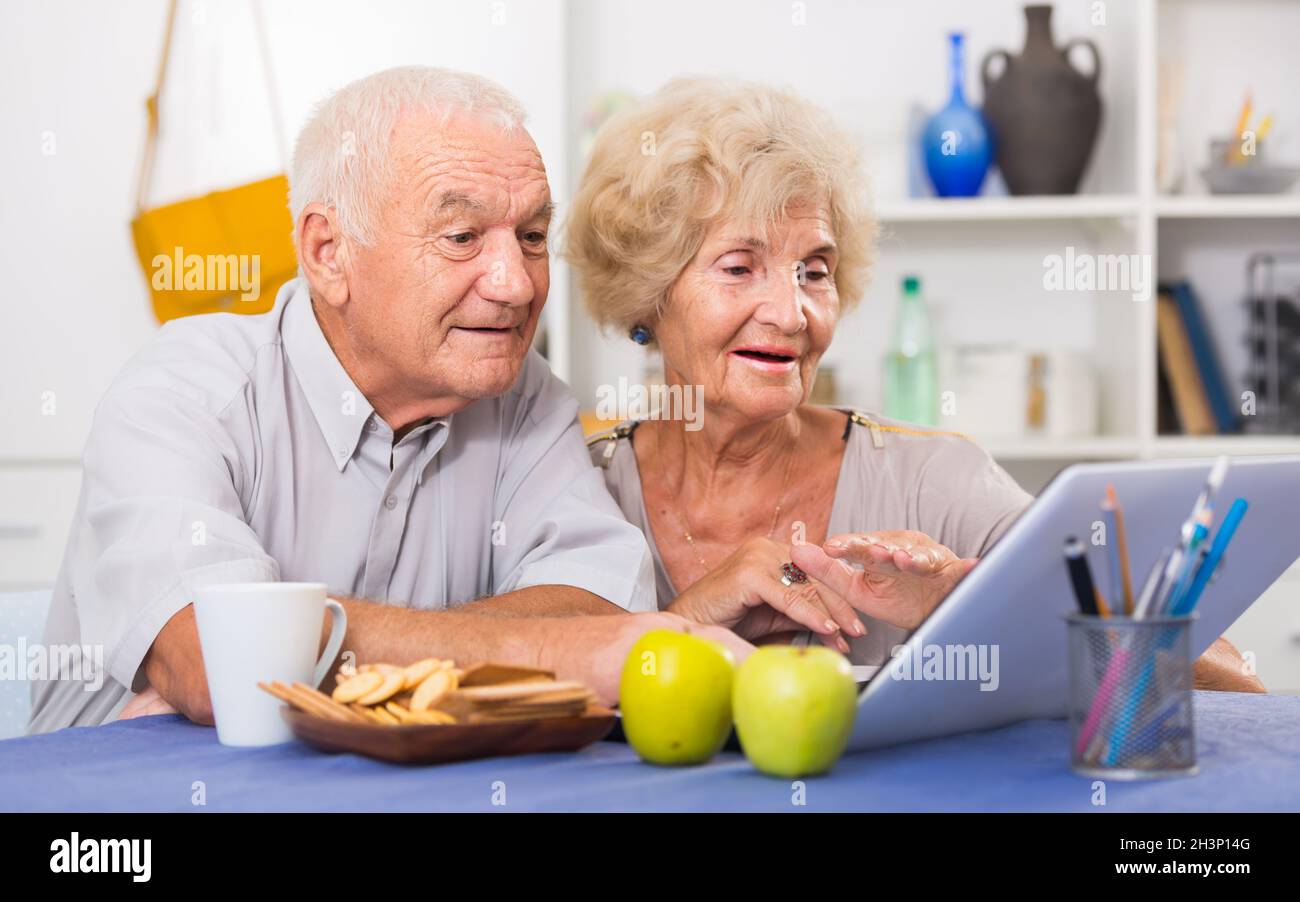 Cheerful mature spouses using laptop at home Stock Photo