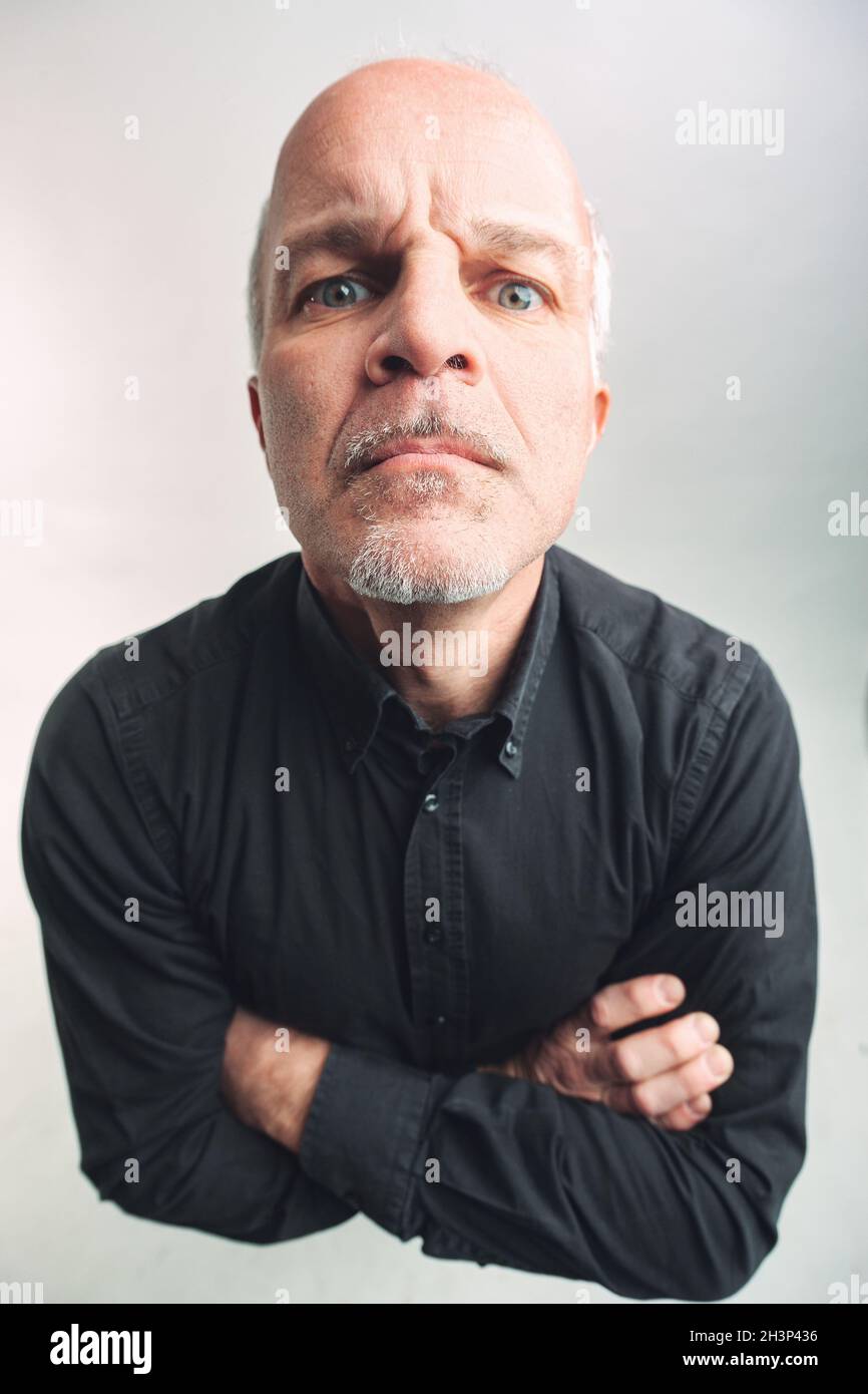 Top down view of a senior man with folded arms staring grumpily at