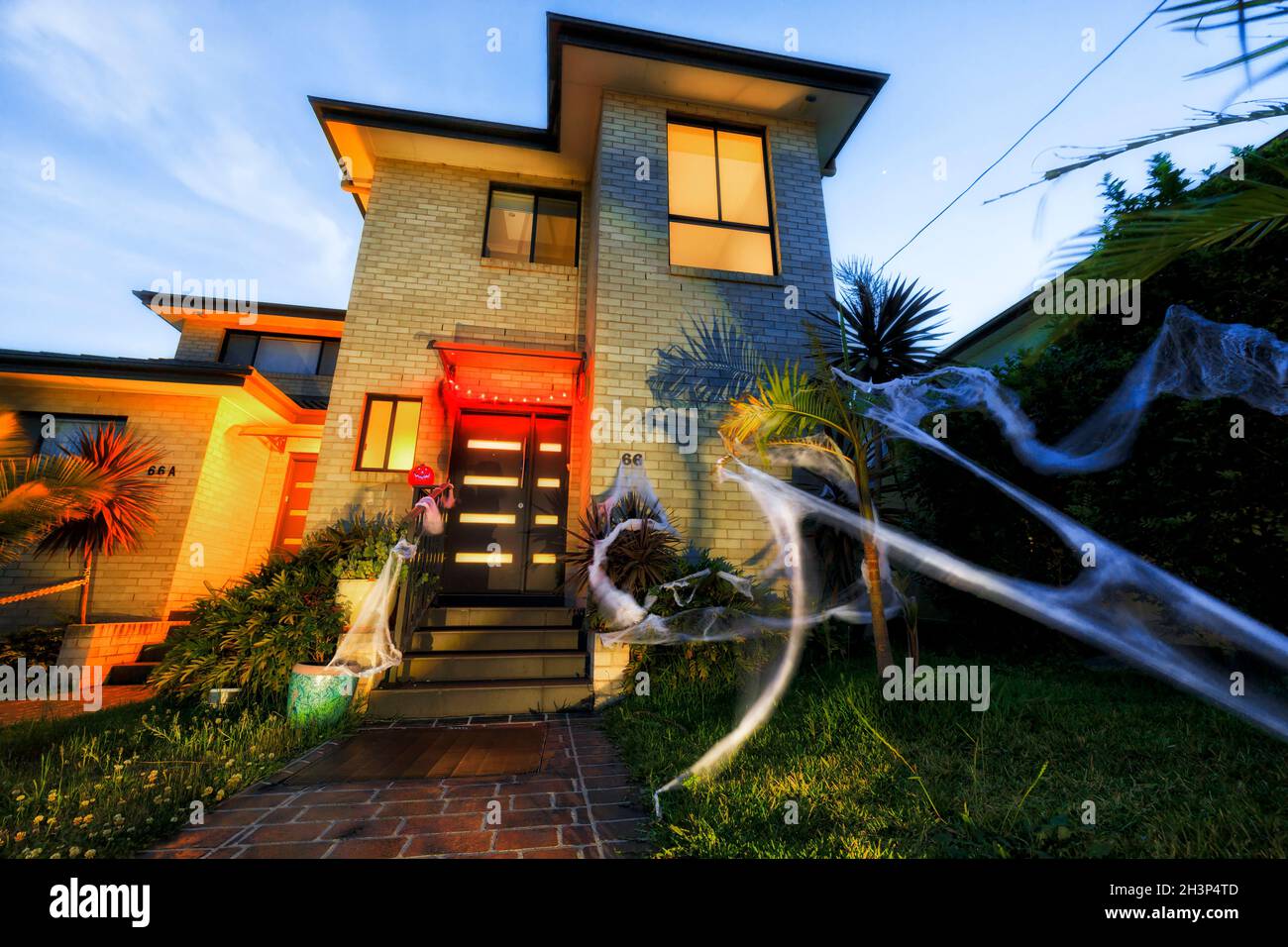 Facade of Halloween decorated house in Australia - green front yard and spider webs everywhere with lights. Stock Photo