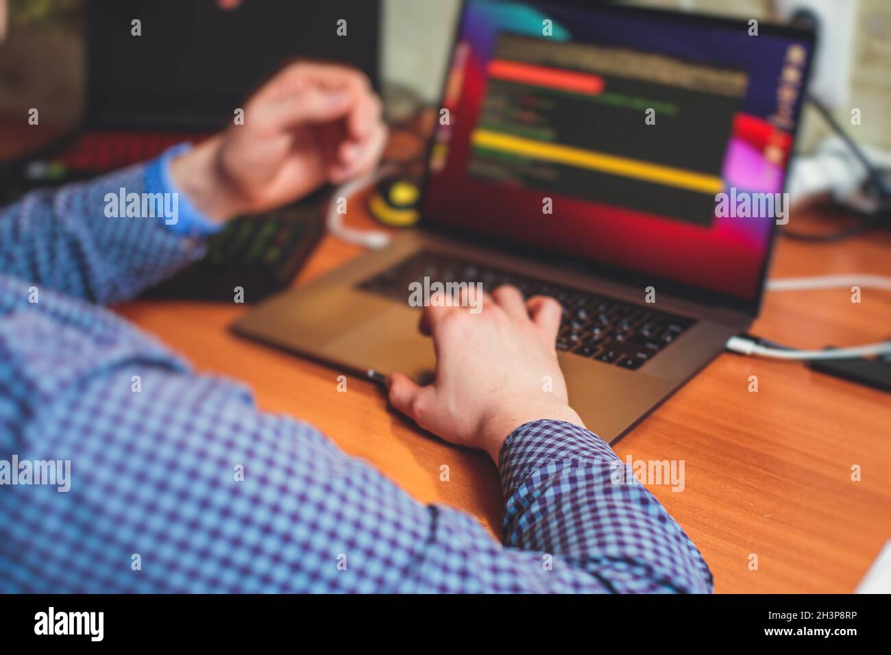 IT developer programmer working and coding on his worplace at home, laptop and desktop monitor pc with coding software program app, remote working fro Stock Photo