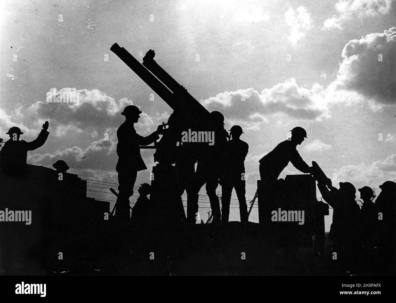 Soldiers silhouetted against the sky prepare to fire an anti-aircraft gun during the Battle of Broodseinde during the  Passchendaele campaign. Stock Photo