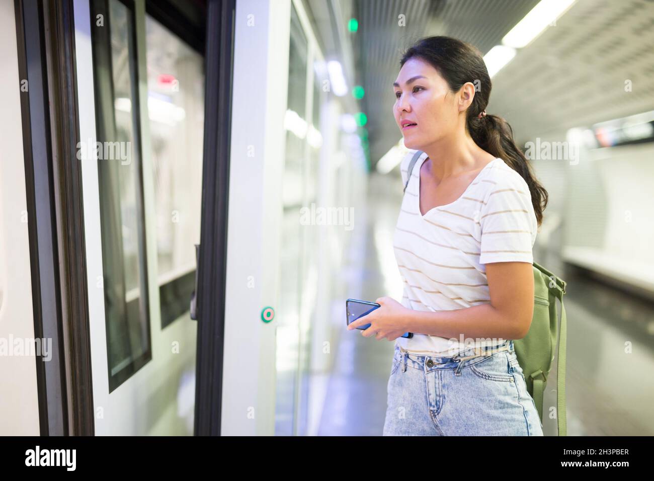 Woman getting on train in subway station Stock Photo