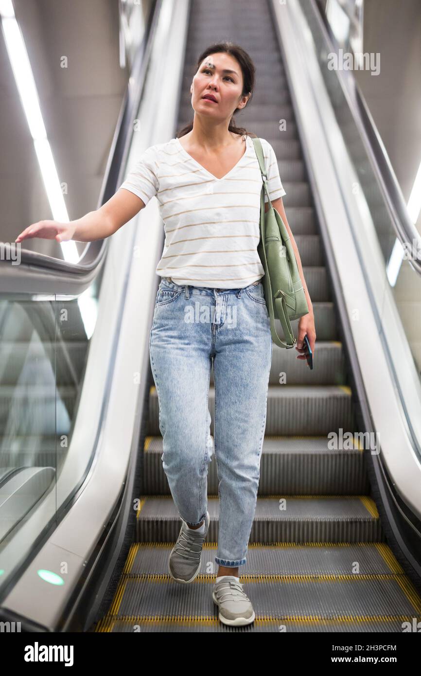 Woman going through escalator Stock Photo