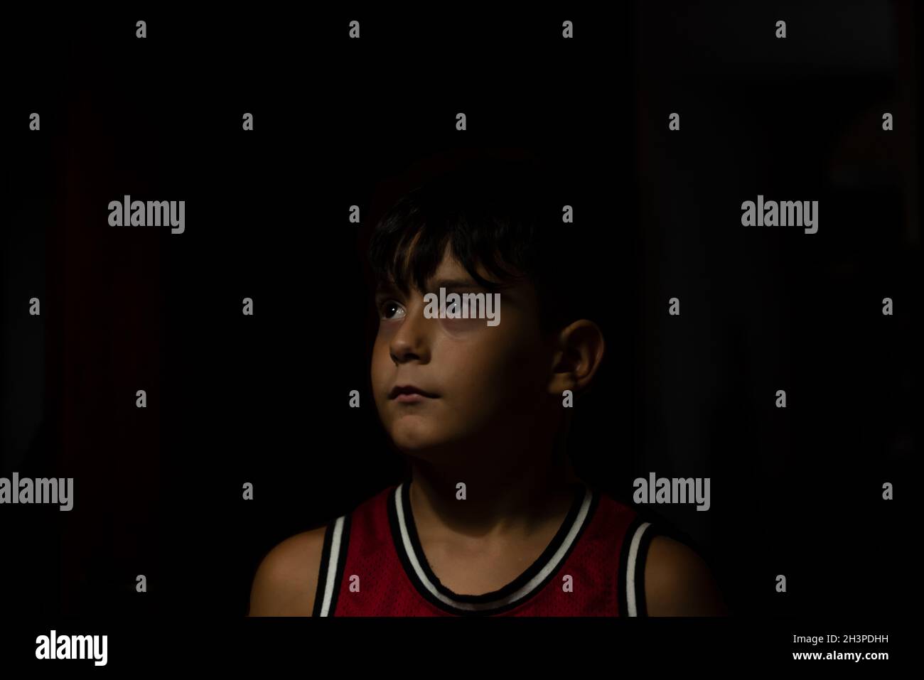 portrait of a boy in a red sports jersey with zenithal light Stock Photo