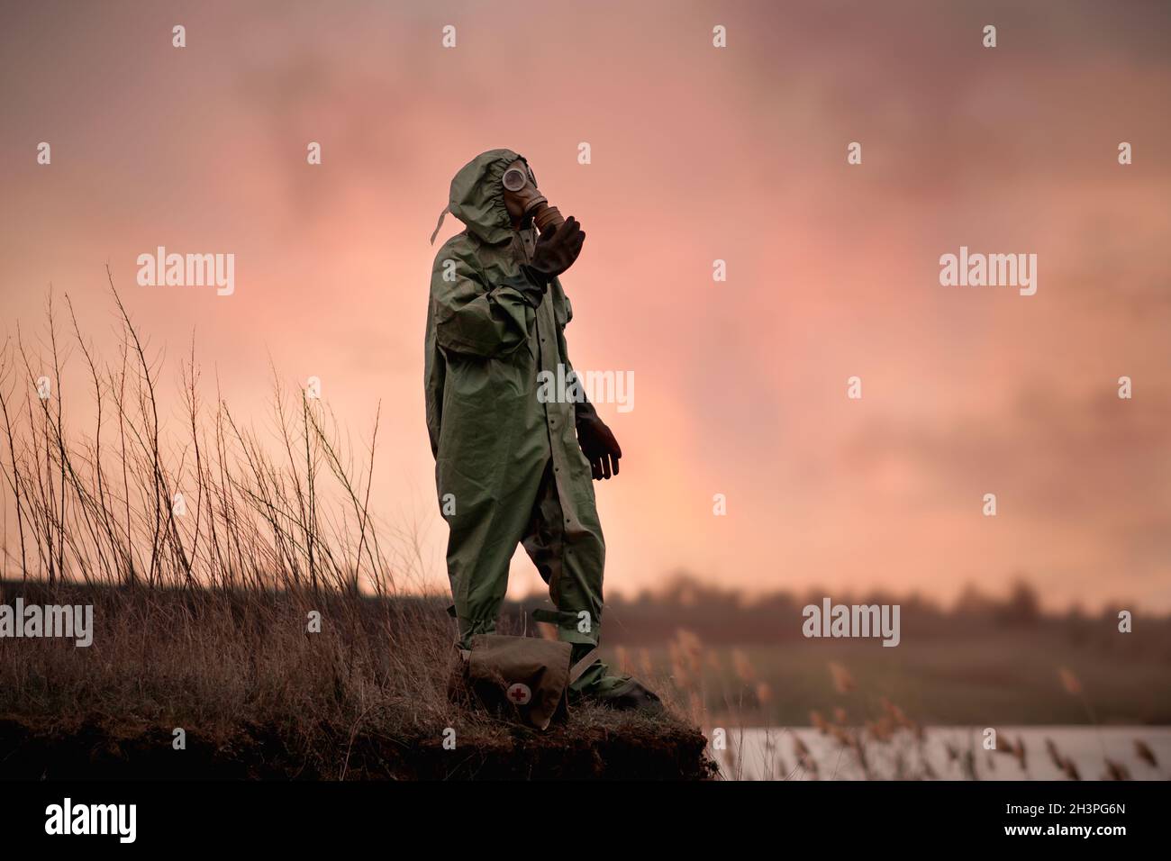 A man in a gas mask and protective suit stands on the edge of the abyss. Stock Photo