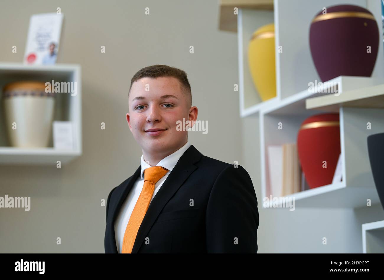 Leipzig, Germany. 18th Oct, 2021. Lennard Wehner stands in front of various urns in a consultation room at Ananke Funerals. As a budding funeral professional, Lennard is in his first year of apprenticeship at the funeral home. Funeral homes have no problems finding new recruits, according to industry sources. (to dpa 'Popular profession: funeral homes have no worries about finding new recruits') Credit: Hendrik Schmidt/dpa-Zentralbild/dpa/Alamy Live News Stock Photo