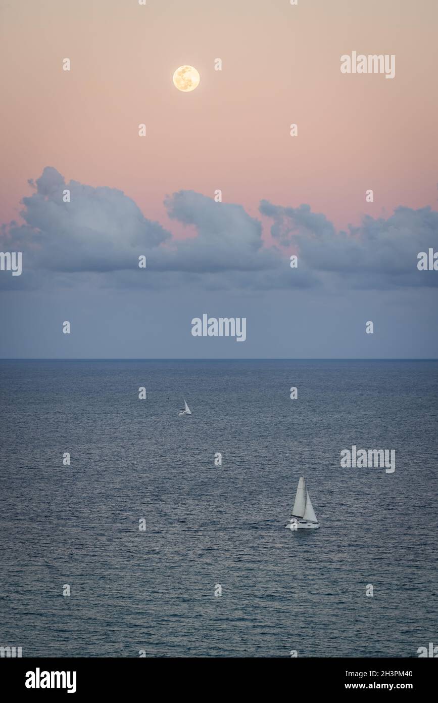 A beautiful setting moon over a sailboat and the Atlantic Ocean. Florida, USA. Stock Photo