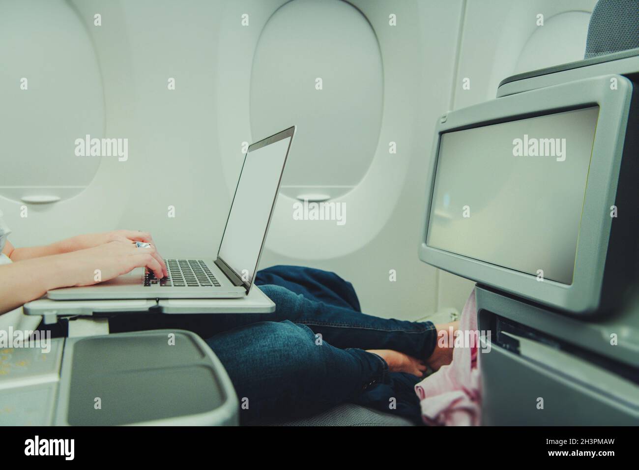 Caucasian Woman Remotely Working on Her Laptop Computer While in Airplane Business Class. Using On Board Internet Access. Stock Photo
