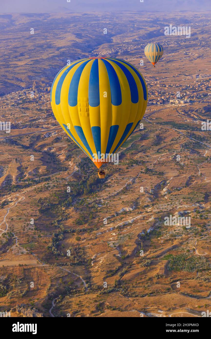 Hot air balloon flying over rocky landscape at sunrise - Cappadocia ...