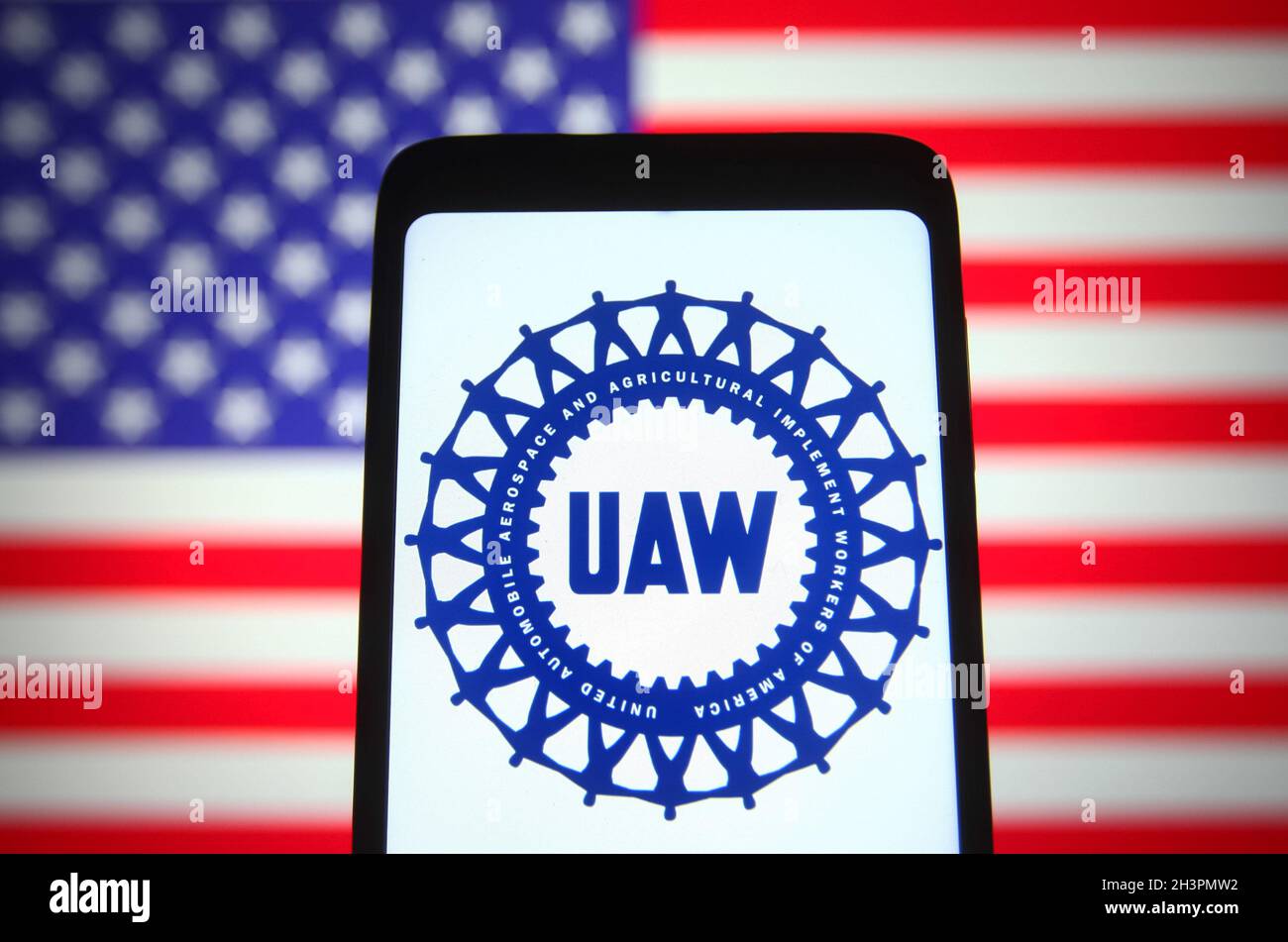 Ukraine. 29th Oct, 2021. In this photo illustration, United Auto Workers (UAW) logo of a US labor union is seen displayed on a smartphone screen and the U.S. flag in the background. Credit: SOPA Images Limited/Alamy Live News Stock Photo