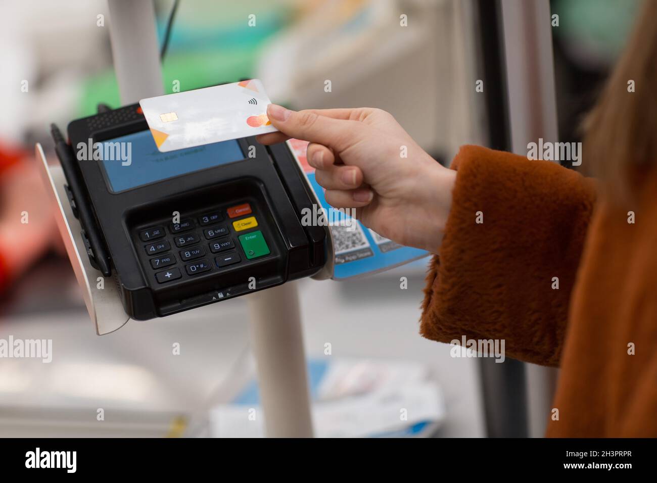 Woman hand with credit bank card pays for purchases at the checkout counter in the store. Contactless payment in new normal shop Stock Photo