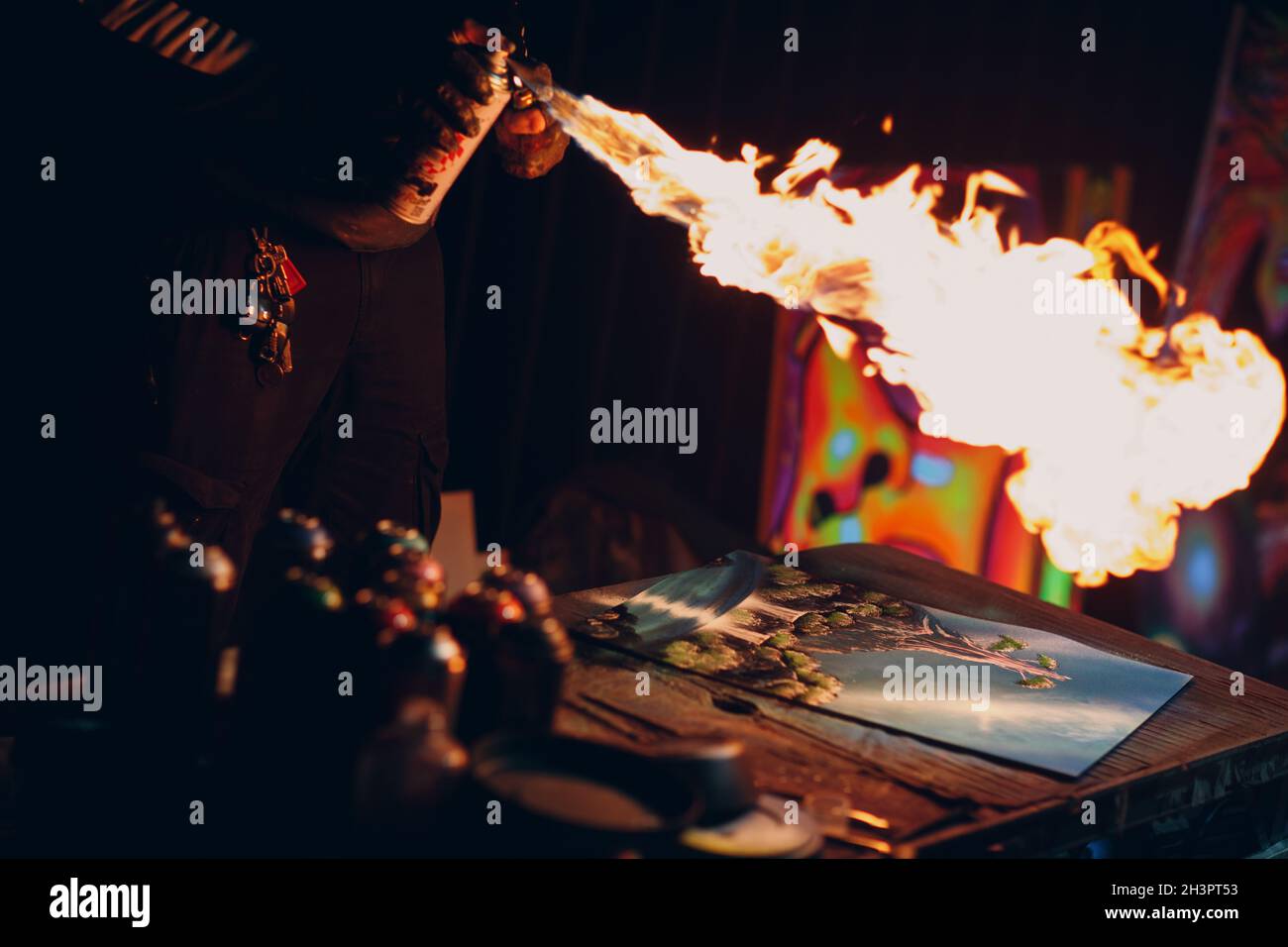 Young street artist finishing his artwork with spray color paint and fire in dark night Stock Photo