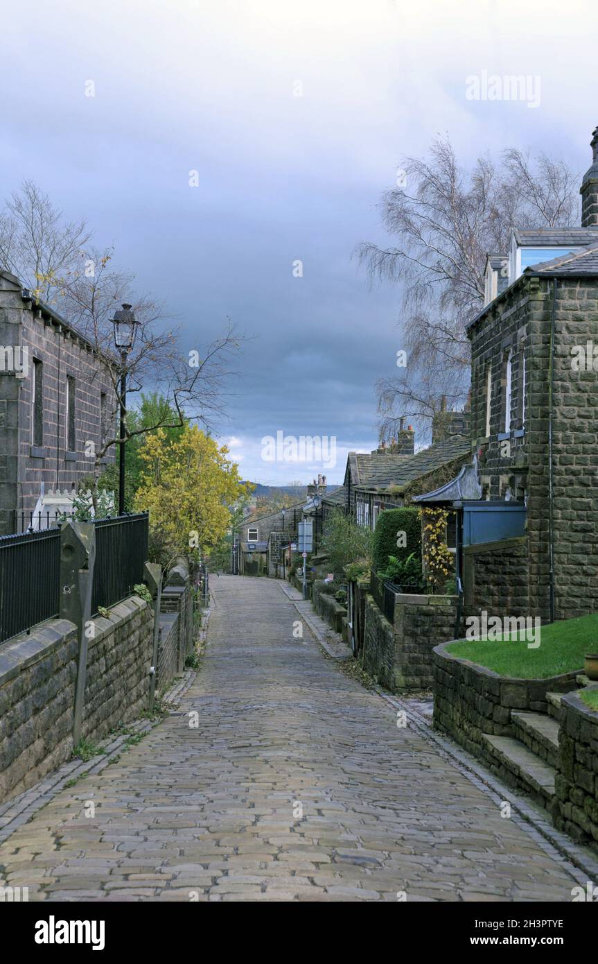 A scenic view of the main street in the village of heptonstall in west yorkshire with old stone houses and a cloudy sky Stock Photo