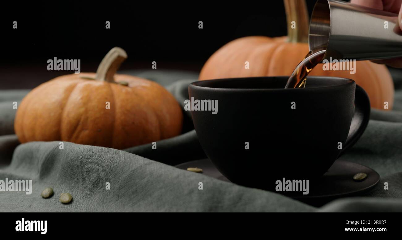 making spiced pumpkin latte in black cup, pour spiced syrup, wide photo Stock Photo