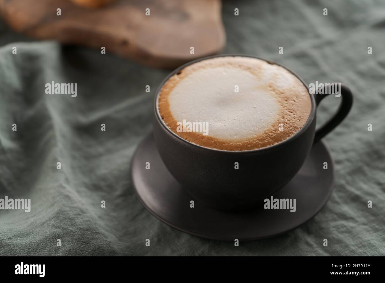 Cappuccino in black cup with ciabatta slices with chocolate spread on background, shallow focus Stock Photo