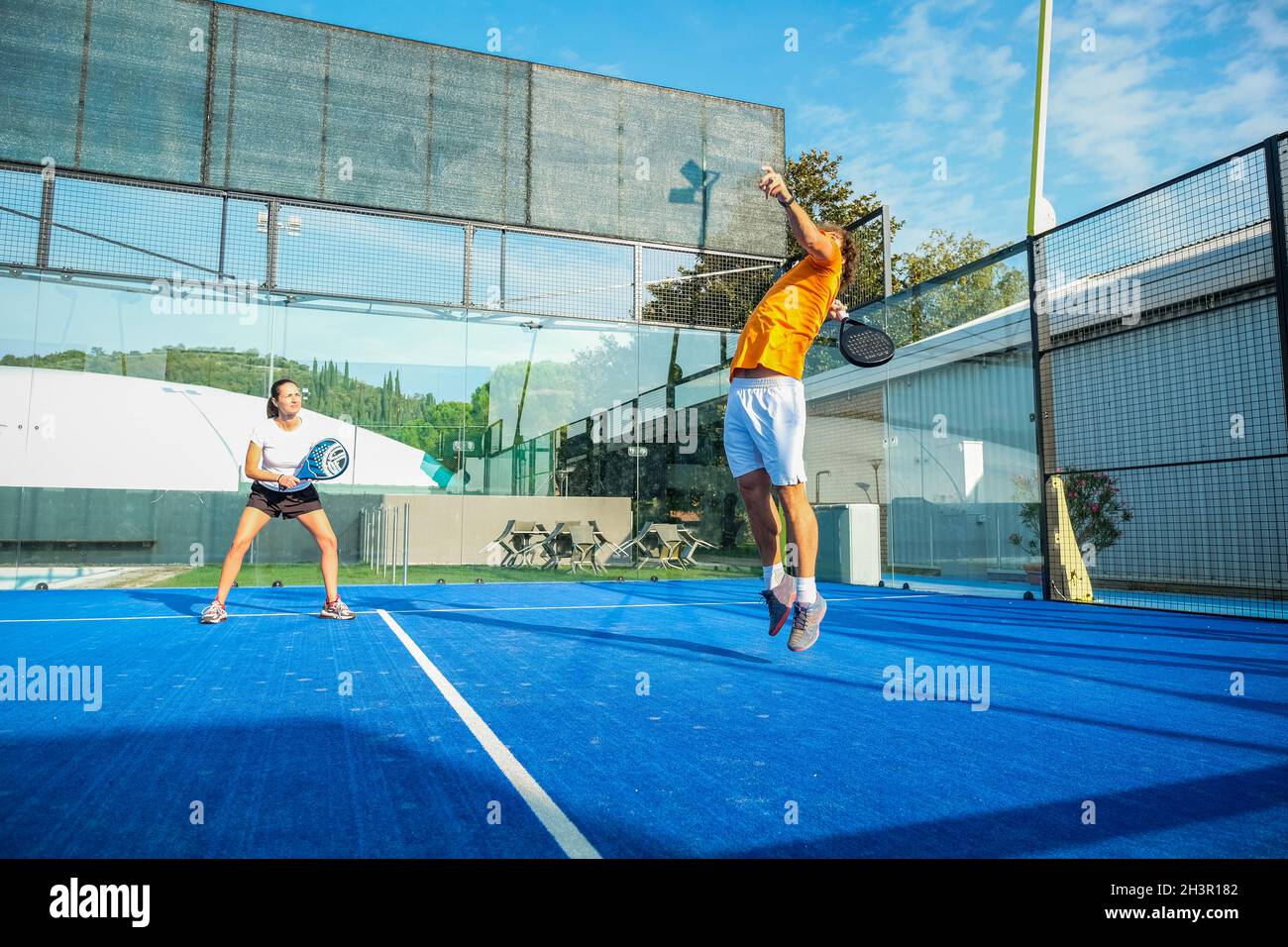 Padel Mix Mixed padel match in a blue grass padel court - Beautiful girl and ...