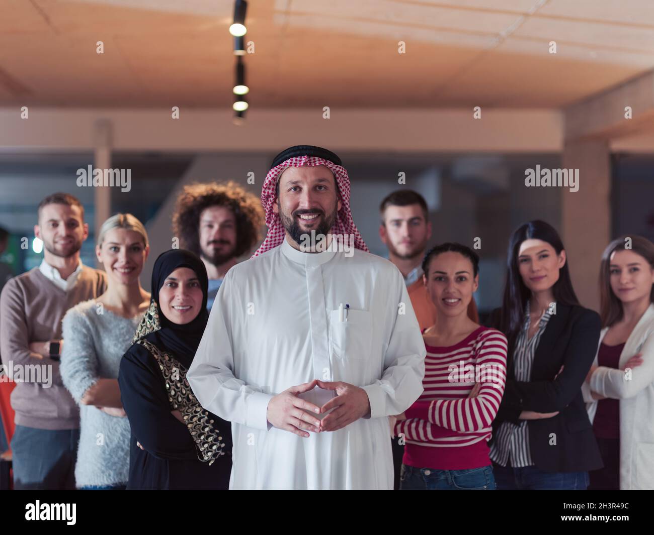 Portrait of multiracial diverse group of businesspeople team standing behind older Arab team leader Stock Photo