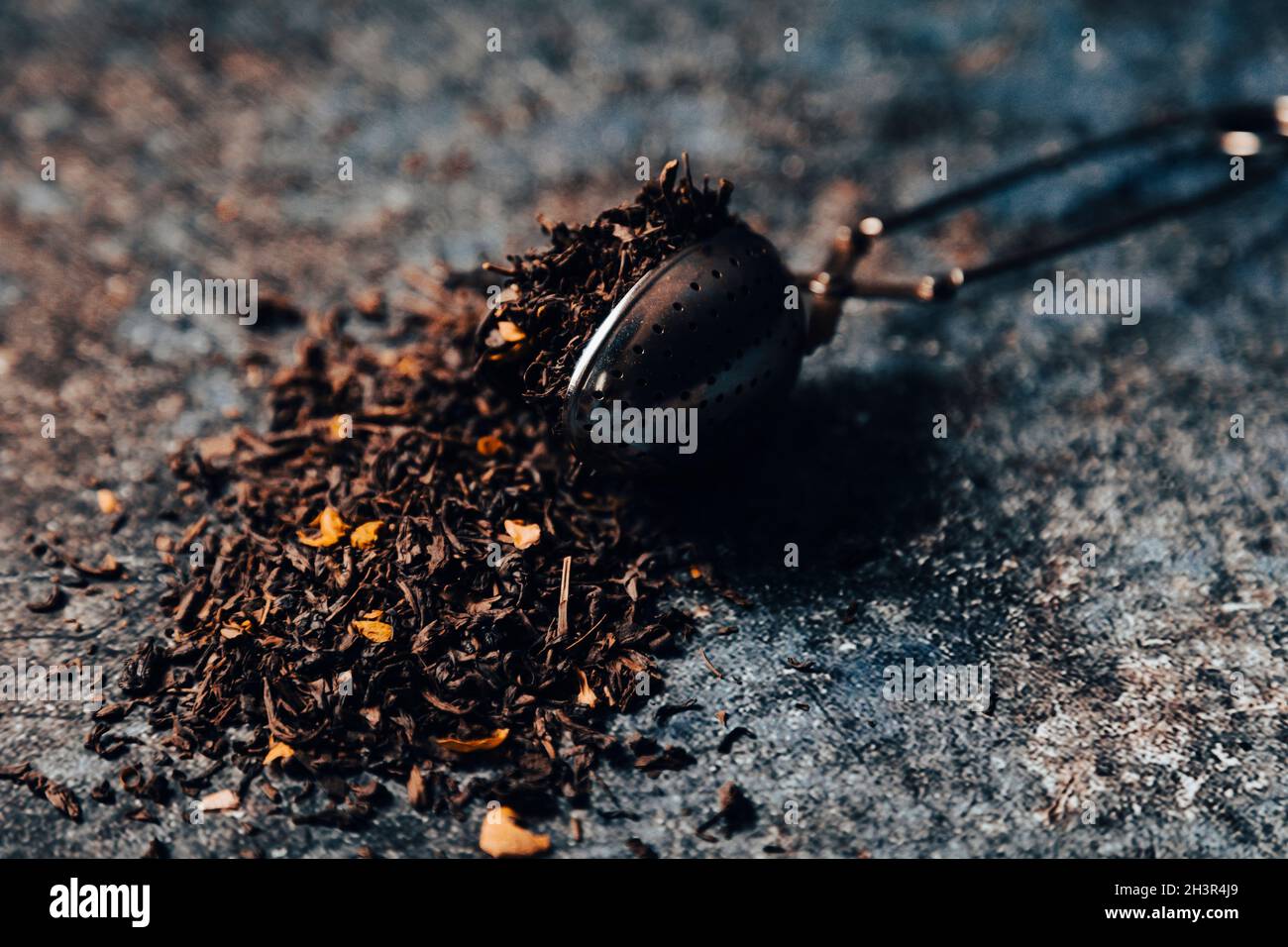 Tea strainer with tea leaves on table. Moody lifestyle image Stock