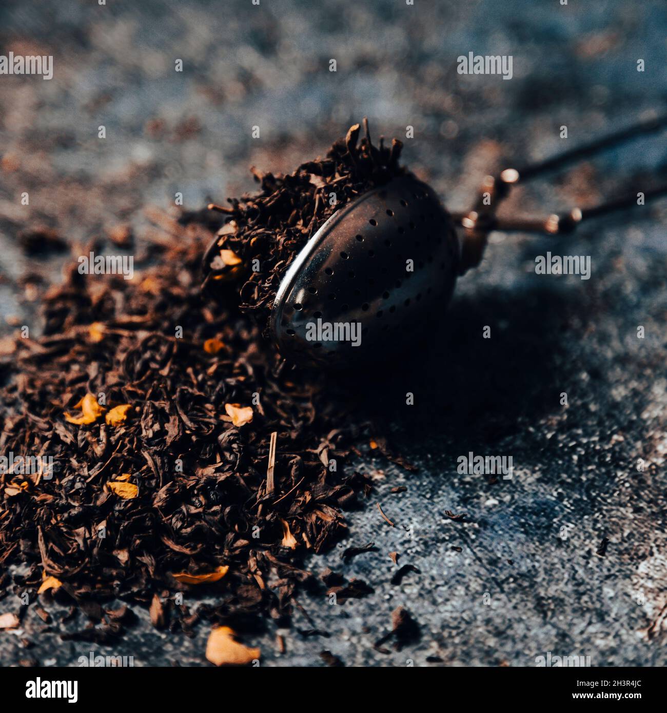 Tea strainer with tea leaves on table. Moody lifestyle image Stock