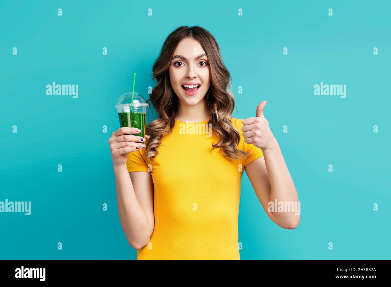Pretty woman with tasty green detox juice on blue background Stock Photo