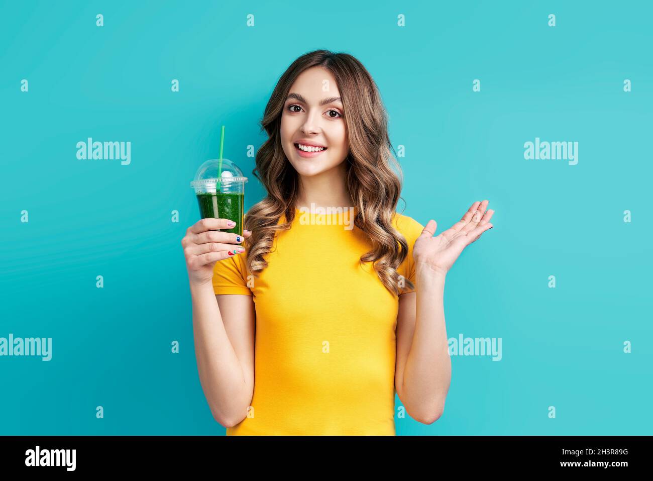 Pretty happy woman with tasty green detox juice on blue background Stock Photo