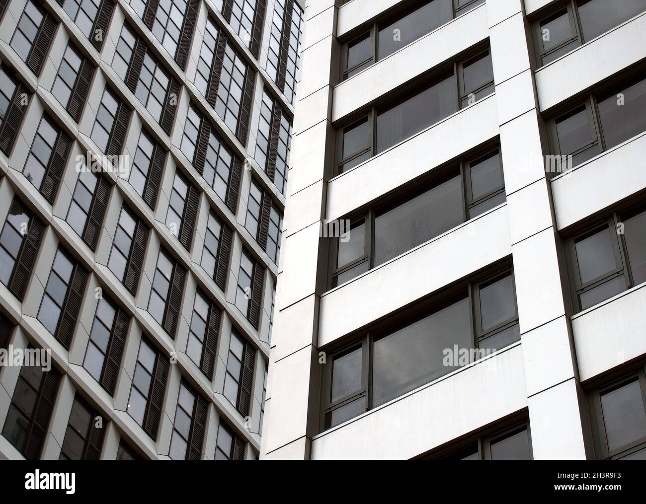 Close up detail of tall high rose modern apartment buildings with white cladding and dark windows Stock Photo