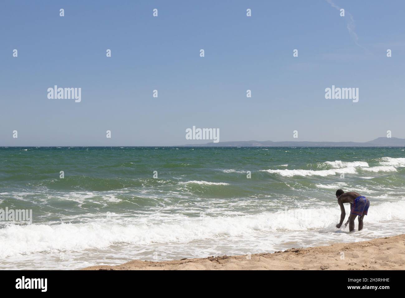 Ocean and black man playing on ocean beach. African man standing next to sea. Man playing on tropical beach of exotic island during summer holiday. Co Stock Photo