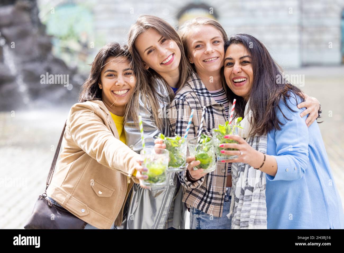 Lifestyle outdoor group of multiethnic beautiful young women clinking cocktail glasses celebrating life love happiness friendshi Stock Photo