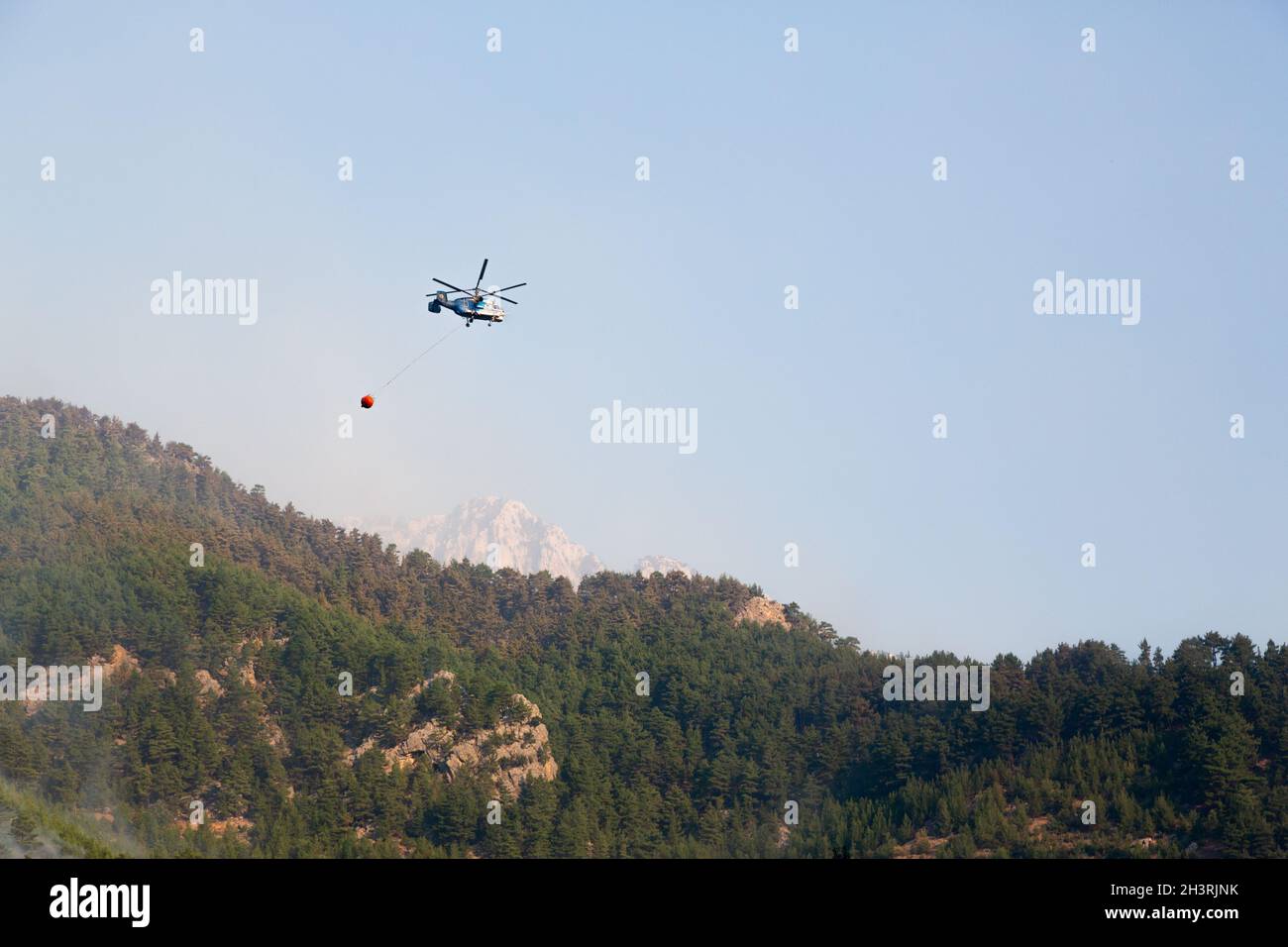 Wildfire helicopter goes to pour water on a fire on the slope of a