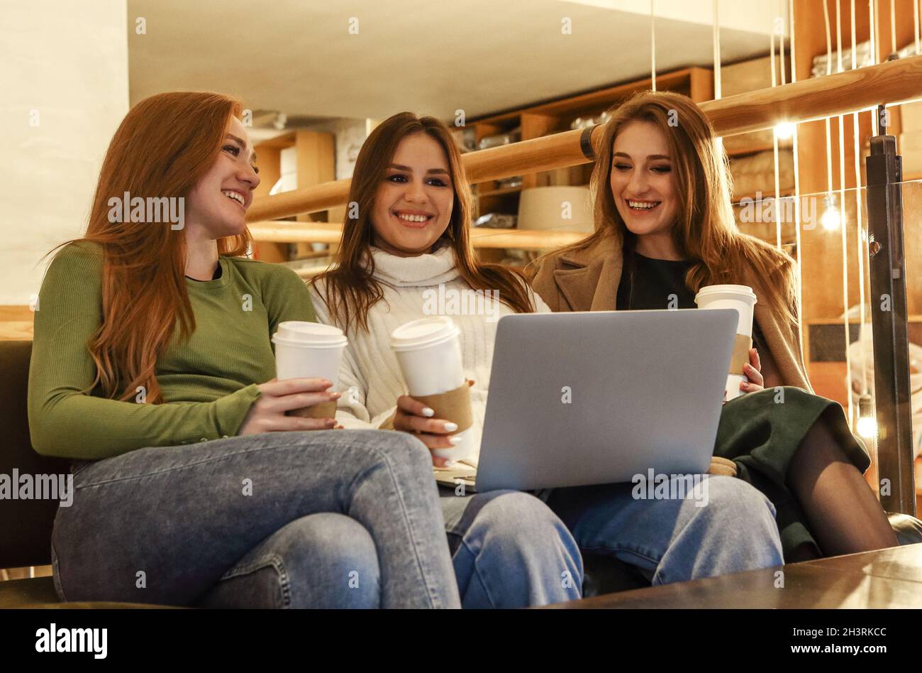 Happy girlfriends using laptop in cafe Stock Photo